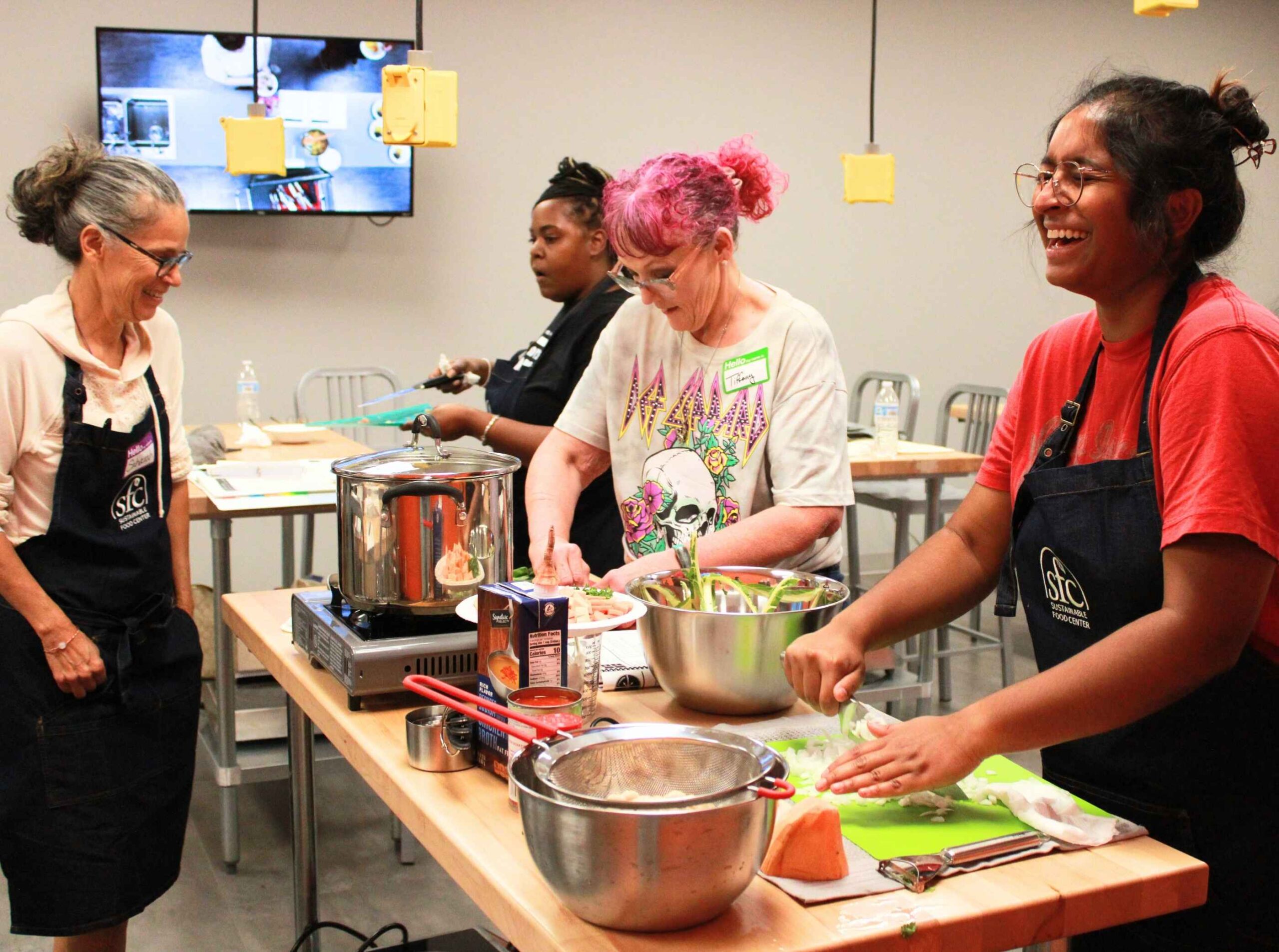 People smile as they chop veggies in The Happy Kitchen class.